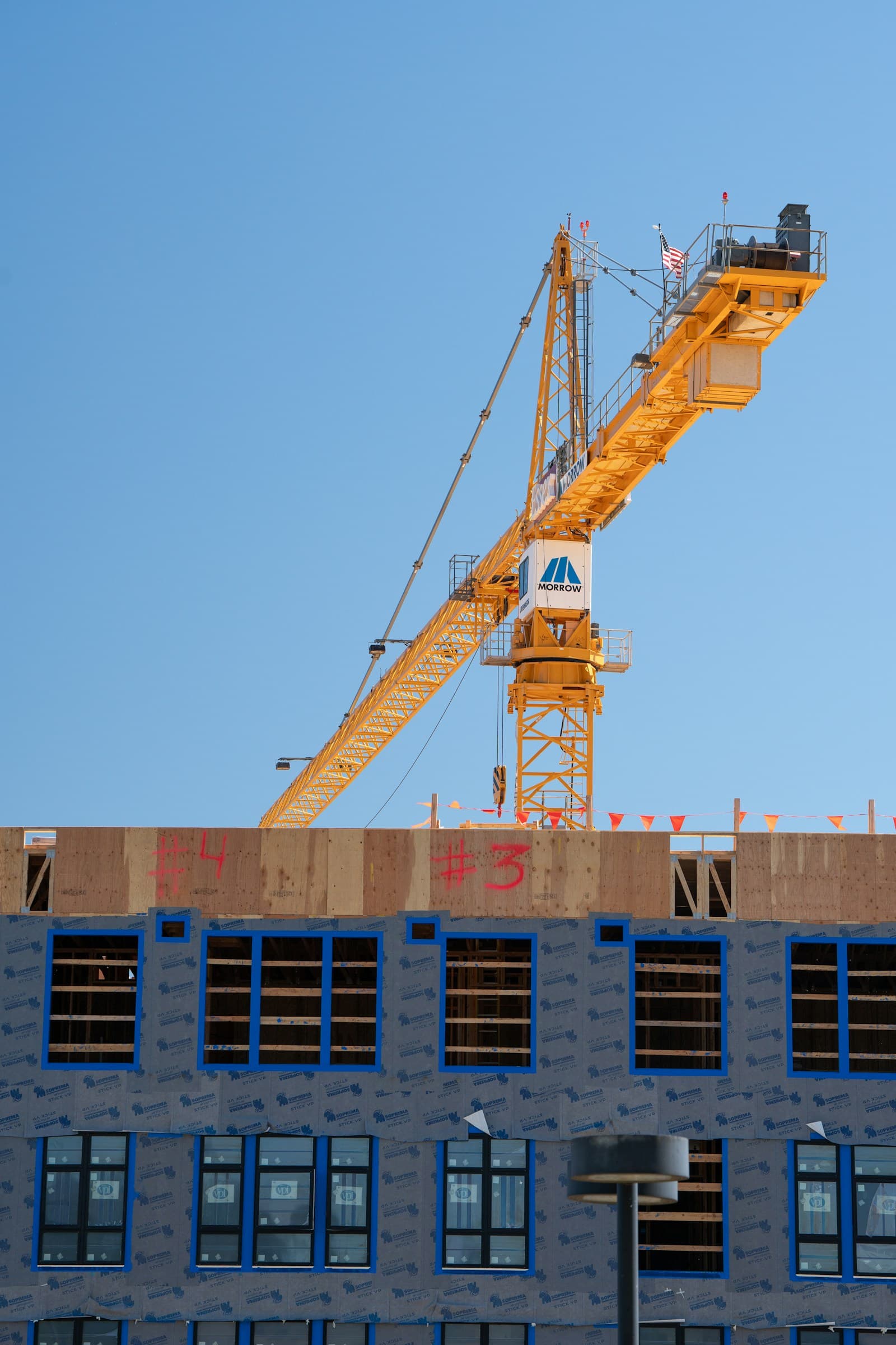 Guindaste amarelo sobre edifício em fase final de obra.