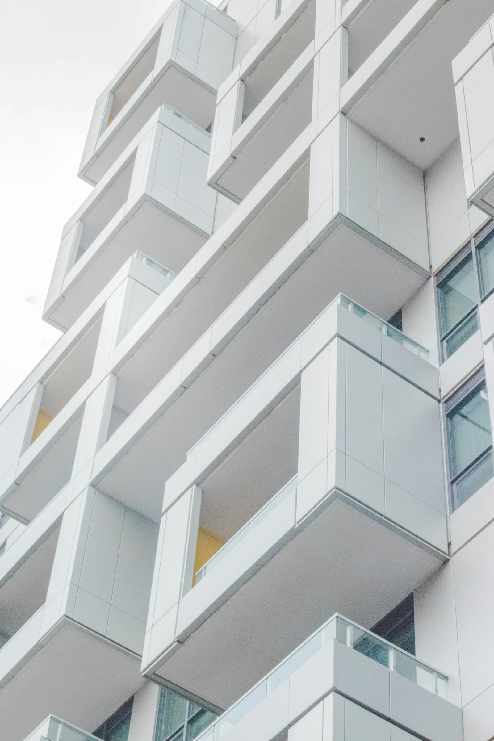 Fachada de edifício residencial branco com varandas.