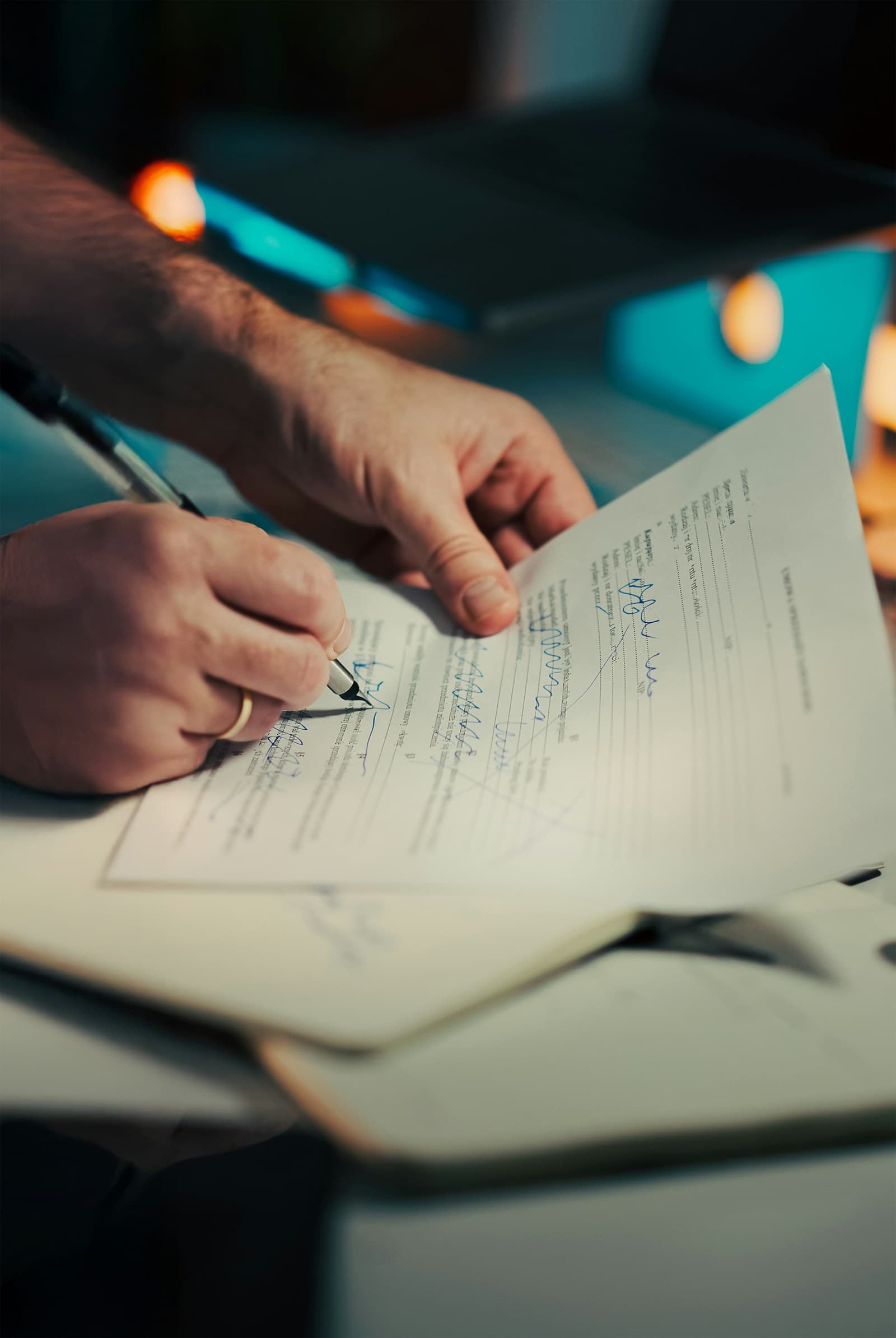 Mãos assinando documentos sobre uma mesa.